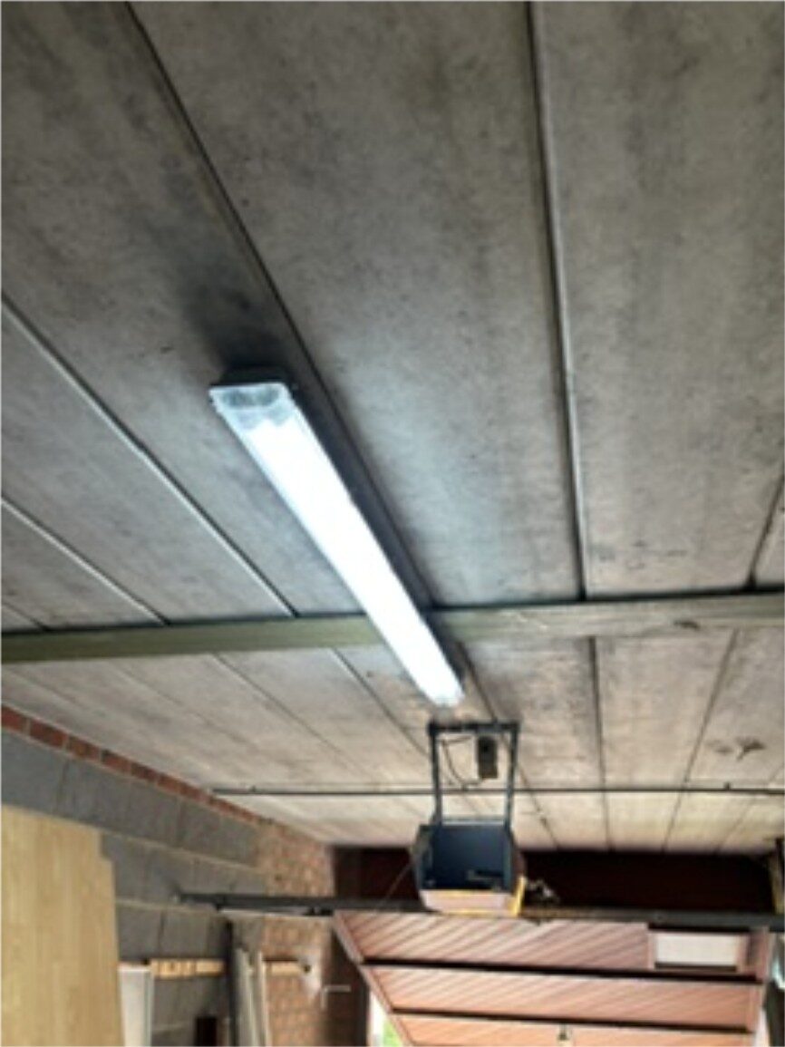 Nieuwe TL-verlichting geïnstalleerd tegen het plafond van een garage